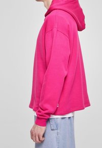 Felpa fucsia con tasca a marsupio, polsini a costine e spalle scese. Tessuto morbido e vestibilità rilassata, progettata per il massimo comfort.