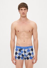 Boxeri pentru bărbați cu un model argyle în nuanțe de albastru, gri și negru. Material din bumbac elastic, cu un tiv albastru pe care este repetat textul mărcii.