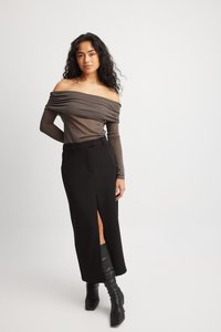 Brun off-shoulder top med rynket design, kombineret med en sort nederdel med højt slids og knæhøje sorte støvler. Glatte teksturer hele vejen igennem.