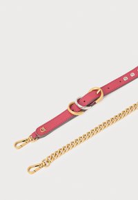 Roza usnjena naramnica z zlatim in srebrnim okovjem, ki ima dva krožna obroča in odstranljivo zlato verigo. Kovinski sponki na obeh koncih.