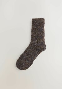 Hnedá ponožka vyrobená z textúrovaného materiálu, s pleteným vzorom a drobnými modrými a zelenými škvrnami, a s rebrovaným lemom pre zvýšenú elasticitu.