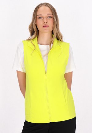 Neon-gelber Fleece-Westen mit hohem Kragen, Reißverschluss und Seitentaschen, getragen über einem weißen T-Shirt. An einer Person getragen.