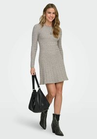 Robe en tricot côtelé gris clair à manches longues, avec un ourlet évasé, associée à un sac à main noir décontracté et des bottines grises texturées.