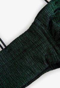 Grön texturerad kort topp tillverkad av samlat tyg med glänsande detaljer. Har tunna svarta remmar och ett mjukt innerfoder.