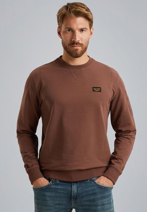 Sweatshirt marron à manches longues et col rond, avec une petite étiquette sur la poitrine. Fabriqué en tissu doux, avec des poignets et un ourlet côtelés.