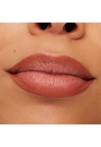 Matte nude leppestift på jevne, fyldige lepper med myk tekstur, som viser en naturlig, subtil definisjon langs konturene.