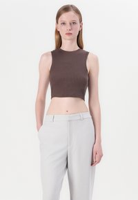 Brown ribbed crop top with a round neckline, paired with light grey tailored trousers, featuring front pockets and a smooth texture.