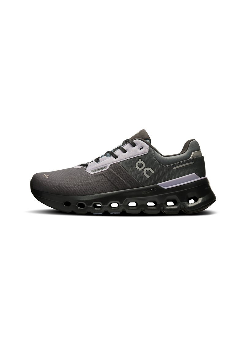 Grauer Sportschuh mit strukturiertem Mesh-Obermaterial, Schnürdesign, ausgeprägter schwarzer Sohle mit Ausschnitten und Logo-Akzent an der Seite.