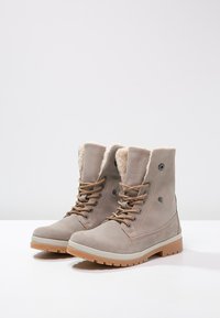 Beige Wildleder-Ankle Boots verfügen über ein Kunstfell-Futter, eine runde Zehenform, metallene Ösen und braune Schnürsenkel, sowie eine strapazierfähige Gummisohle.