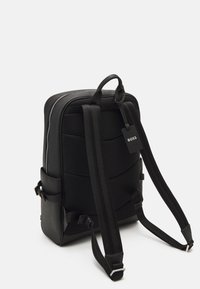 Black backpack with textured fabric, padded back, adjustable straps, and a side pocket. Features a zippered main compartment and brand tag.