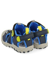 Chanclas para niños en azul y negro con acentos amarillos, que presentan una parte superior texturizada, correas ajustables y una suela de goma de color claro.