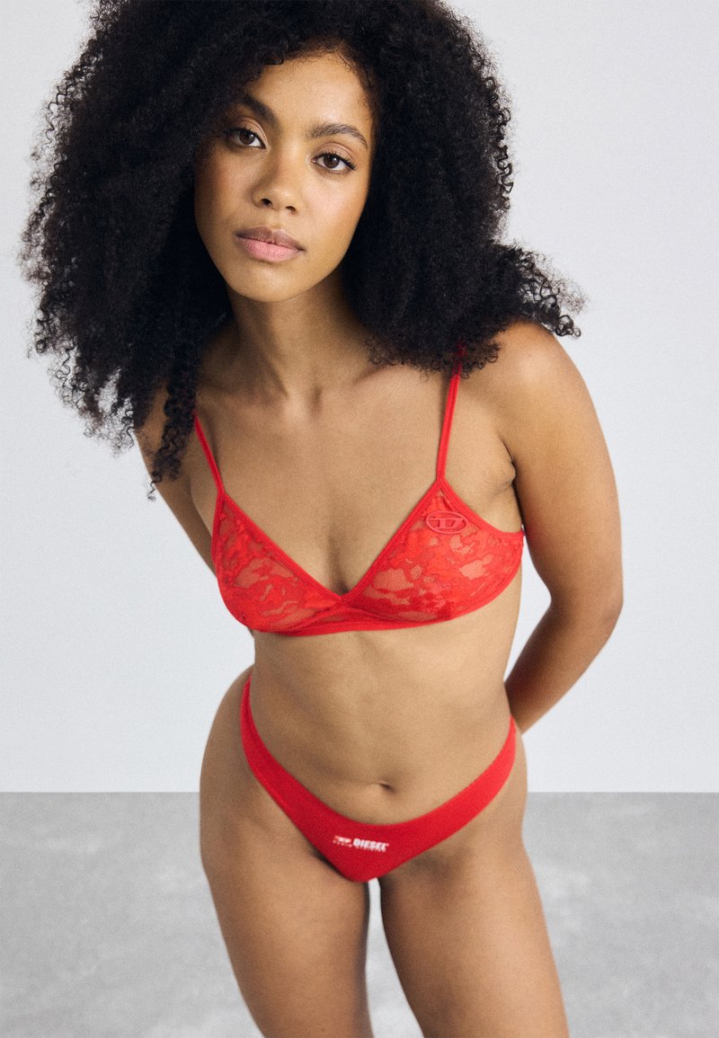 Rode kanten bralette met dunne bandjes en een driehoekige vorm, gecombineerd met een bijpassende rode low-rise thong met logo-detail.