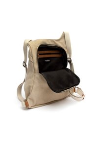Beżowy plecak z tkaniny z regulowanymi ramiączkami, otwarty zamek z przodu odsłaniający czarne wnętrze i brązowe kieszenie na zamek w środku.