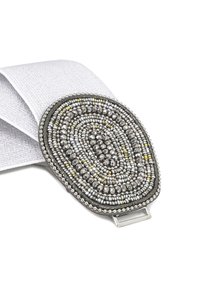 Fibbia ovale in perline con dettagli in argento e oro, montata su una fascia elastica bianca. La fibbia presenta un intricata lavorazione di perline e texture.