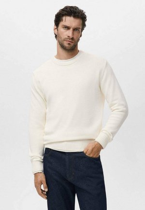 White knit sweater with a crew neckline and ribbed cuffs and hem, paired with dark denim jeans. Smooth texture, simple design.