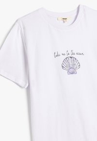 Hvid t-shirt med kort ærme, der har en lilla musling og teksten "tag mig med til havet" trykt på brystet.