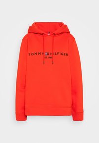 Felpa rossa con cappuccio realizzata in tessuto morbido, caratterizzata da un grande logo nero con la scritta "TOMMY HILFIGER EST. 1985" e cordini al collo.