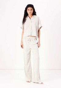 Ensemble à rayures composé d'un haut à manches courtes avec boutons et d'un pantalon à cordon. Tissu léger en crème avec de douces rayures grises.