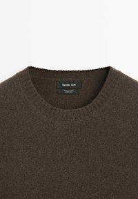 Dunkelbrauner Cashmere-Pullover mit Rundhalsausschnitt, geripptem Kragen und sichtbarem Markenetikett "Massimo Dutti" im Ausschnitt.