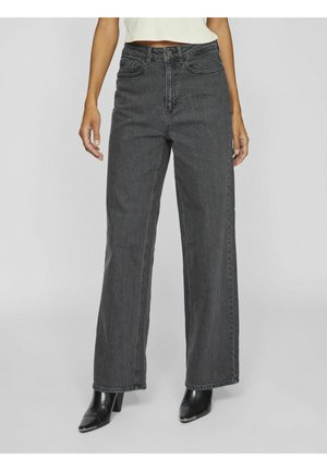 High-waisted, wide-leg jeans in dark gray denim with a textured finish. Features classic five-pocket design and belt loops, paired with black heels.