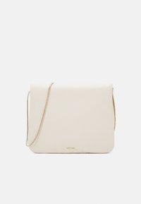 Kabelka v měkkém krémovém materiálu s přehybem, zlatým řetízkovým ramínkem a decentním logem na spodní části. Hladká textura.