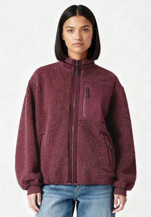 Bordeauxrote Fleecejacke mit hohem Kragen, Reißverschlusstaschen und langen Ärmeln. Verfügt über eine weiche, strukturierte Oberfläche und ein kontrastierendes Paneel auf der Brust.