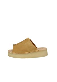 Sandal in suede marrone, a slip-on con lati aperti, dettagli cuciti e una suola in gomma di colore chiaro. Design minimalista, texture liscia.