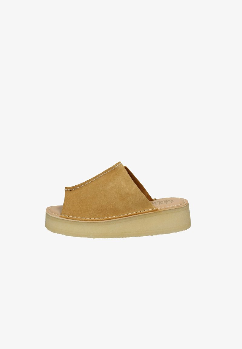 Sandal in suede marrone, a slip-on con lati aperti, dettagli cuciti e una suola in gomma di colore chiaro. Design minimalista, texture liscia.