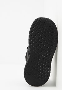 Svart sportskosula med ett texturerat diamantmönster för grepp. Lätt material med en slank, minimalistisk design.