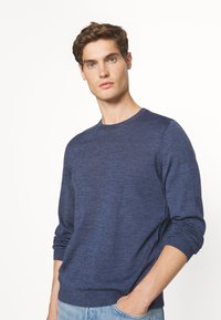 Pulover tricotat de culoare bleu închis, cu guler rotund, mâneci lungi și manșete cu nervuri. Textură netedă, croială clasică și design casual.