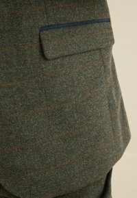 Wollblazer mit grünem Hahnentritt-Muster, versehen mit orangefarbenen und blauen Streifen, einer einzelnen Brusttasche und einer strukturierten Oberfläche.