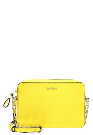 Sac bandoulière rectangulaire jaune vif avec chaîne argentée et sangle en cuir, avec un petit logo argenté "Calvin Klein" sur le devant.