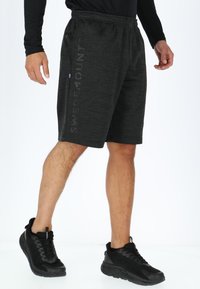 Zwarte sportshorts met een zachte textuur, voorzien van een elastische tailleband en zijzakken. De tekst SWEDEN MOUNT is afgedrukt op de zijkant.