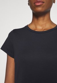 T-shirt bleu marine à col rond avec manches courtes, fabriqué en tissu coton doux. Présente une texture lisse et un design ajusté, mettant en avant une esthétique simple.