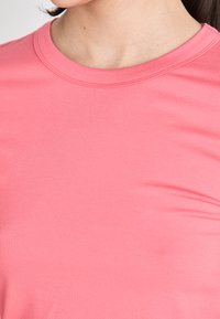 T-shirt de manga curta, decote redondo, na cor rosa brilhante sólida, feita de um tecido suave e elástico com um design ajustado.