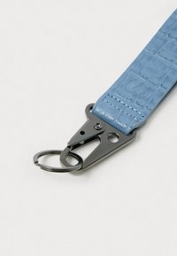 Blå tekstureret rem med krokodillemønster, forsynet med en sort metalclip og ring til fastgørelse. Glat overflade med sydde kanter.