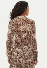 Camicia a maniche lunghe marrone e beige con un motivo a macchie di leopardo, realizzata in tessuto leggero e con colletto arrotondato sul retro.