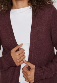 Burgundy knit cardigan with a v-neckline, ribbed cuffs, and an open front. Accentuates a textured, soft fabric.