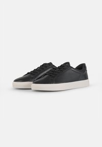 Sneakers in pelle nera con finitura liscia, design low-top, punta arrotondata e suola di gomma bianca a contrasto. Presentano una classica chiusura con lacci.