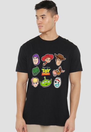Man wearing black Toy Story t-shirt with cartoon faces of Buzz Lightyear, Jessie, Woody, Rex, Bullseye, Bo Peep, alien, and Forky.