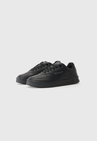 Baskets noires en cuir texturé, avec bout rond, semelle en caoutchouc plate, fermeture à lacets et détail de logo sur le côté.