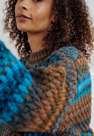 Suéter tejido que presenta una mezcla de tonos azul, marrón y turquesa. Patrón texturizado con un cuello redondo y mangas largas.