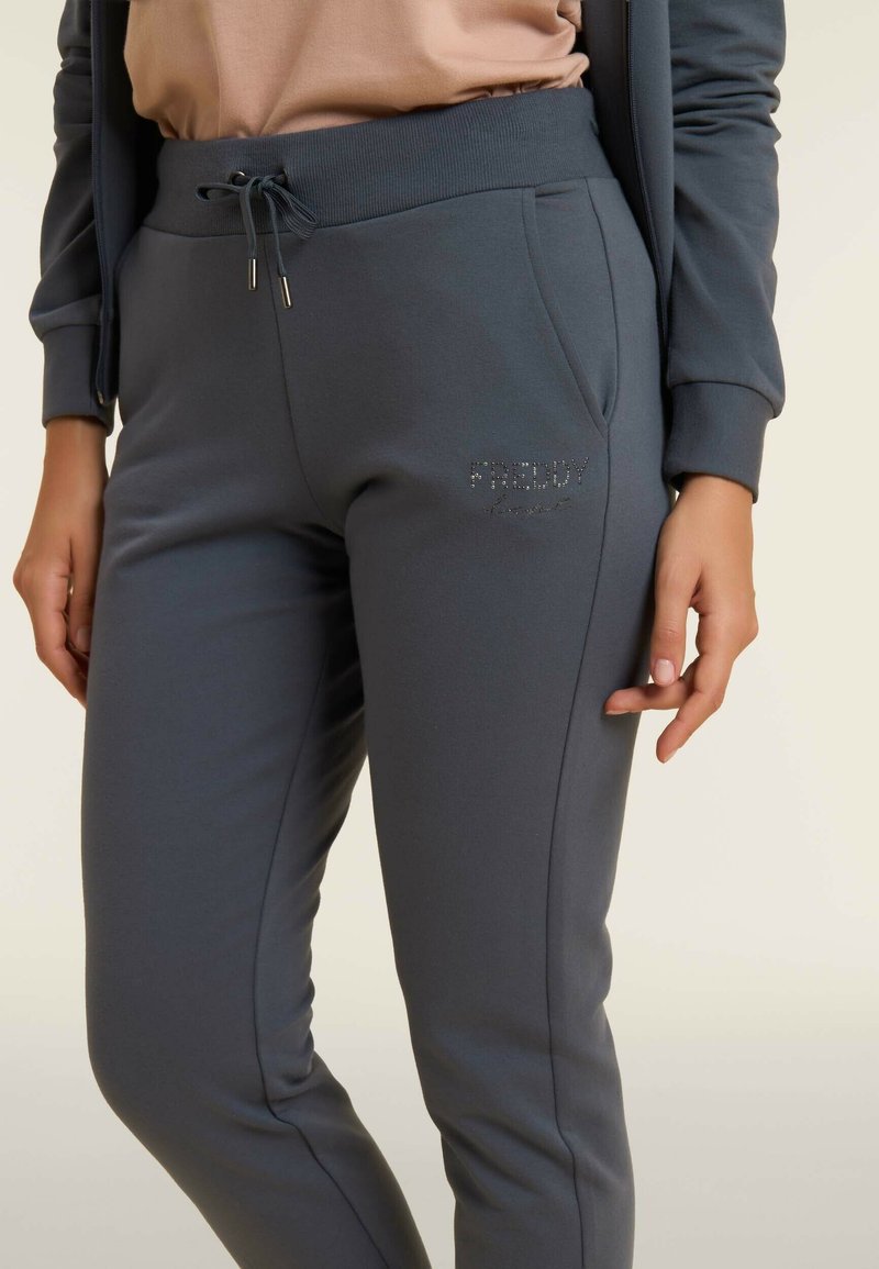 Pantalons de survêtement grises en matériau doux avec une taille élastique, poches latérales et un logo "FREDDY" en strass sur le devant.