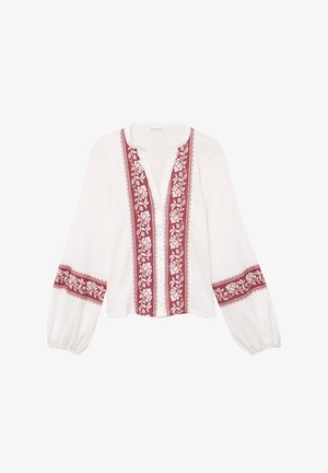 Blouse blanche avec manches longues bouffantes et encolure arrondie. Présente une broderie florale rouge sur le devant et les manches. Fermeture à boutons sur le devant.
