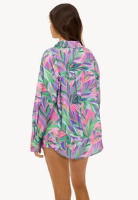 Lange mouwen blouse van lichtgewicht stof, met een levendig patroon van meerkleurige bladeren in tinten groen, roze en paars.