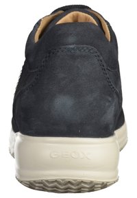 Baskets en daim bleu marine avec une finition texturée, semelle en caoutchouc blanche et branding visible. Présente un design basse et une doublure intérieure lisse.