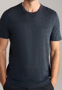 Granatowa koszulka z krótkim rękawem z okrągłym dekoltem, teksturowanym materiałem i luźnym krojem. Prosty design bez zauważalnych wzorów czy akcentów.