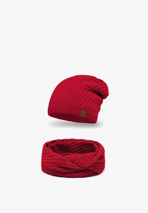 Czerwona, dziana czapka beanie o luźnym kroju i prążkowanej strukturze, w zestawie z dopasowanym kręconym szalikiem w nieskończoność. Oba elementy mają subtelny połysk.