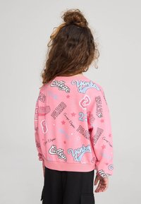 Felpa rosa con varie stampe di testo in blu e nero, tra cui "Parigi" e "College", con orlo a costine e vestibilità comoda.