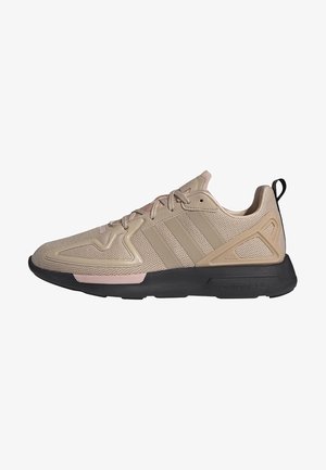 Zapatillas deportivas beige con parte superior de malla, acentos rosas, suela de goma y diseño de tres franjas. Presentan un panel texturizado y un tirador.